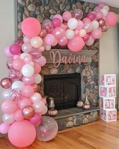 a fireplace decorated with pink and white balloons for a baby's first birthday party