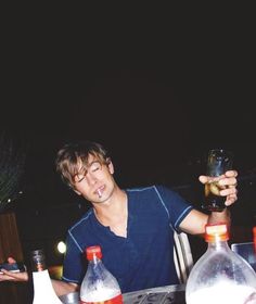 a man sitting at a table with bottles and drinks