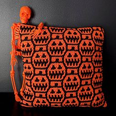 an orange and black crocheted skull bag