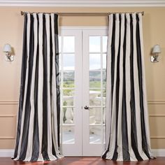 black and white striped curtains hanging in front of a door with wood flooring next to it