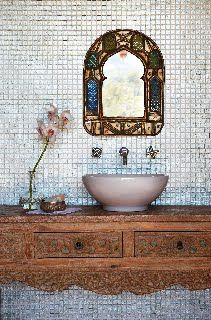 a white sink sitting under a mirror on top of a wooden counter next to a vase