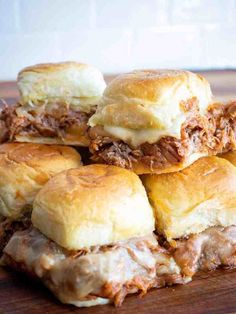 a pile of sandwiches sitting on top of a wooden cutting board next to each other