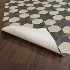 a black and white checkered rug on the floor with wood grained flooring