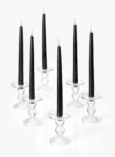 six candles are lined up in glass holders