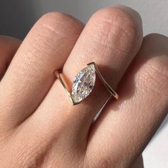 a woman's hand wearing a gold ring with a pear shaped diamond