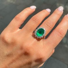 a woman's hand with an emerald and diamond ring