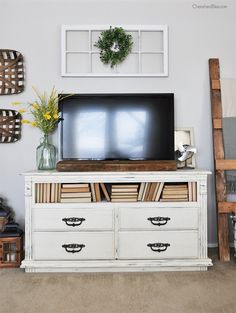 a tv sitting on top of a white dresser