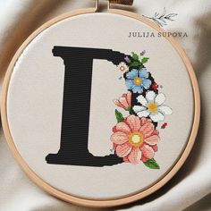 a cross stitch pattern with the letter i in it's center surrounded by flowers