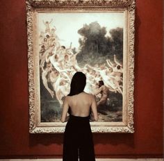 a woman standing in front of a painting