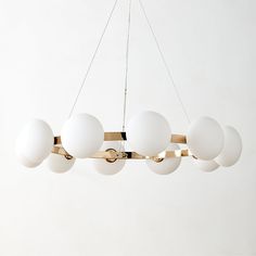 a modern chandelier with eight white balls hanging from it's brass frame