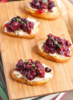 three cranberry tarts on top of a wooden cutting board next to other food items