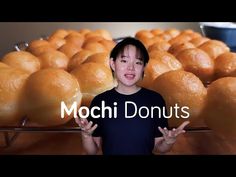 a young boy standing in front of rows of donuts with the words mochi donuts over them