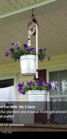 two buckets with flowers hanging from them on the porch, one is filled with purple pansies