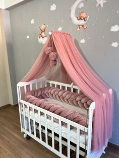 a baby crib with pink curtains and teddy bears on the wall above it,