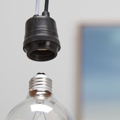 a light bulb is suspended from the ceiling by a black wire and an electrical outlet