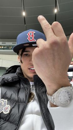 a man in a boston red sox baseball cap giving the peace sign with his hand