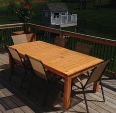 a wooden table sitting on top of a wooden deck next to a green lawn area