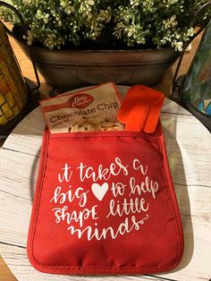 a potted plant sitting on top of a wooden table next to a red bag