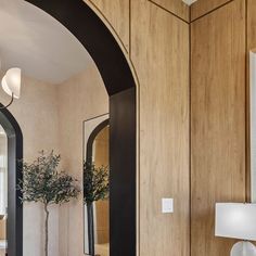 an arched doorway leads to a bathroom with wood paneling and marble countertops, along with a vase filled with flowers