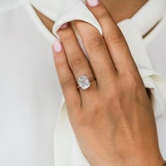 a woman's hand with a diamond ring on her left wrist, wearing a white shirt