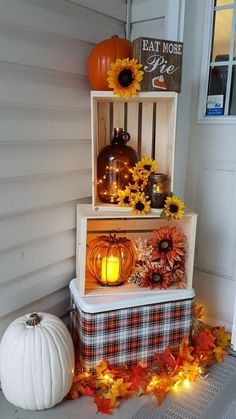 three wooden crates with pumpkins and sunflowers on the front porch for display