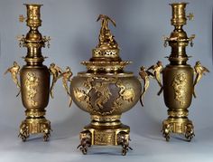 three golden vases with figures on them sitting next to each other