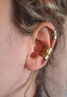 a close up of a person's ear with two gold rings on top of it