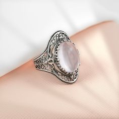 "This gorgeous handmade filigree art statement ring will draw all the right kind of attention. Made of sterling silver, it is oxidized and highly polished.  The ring face is 0.97\" / 24.70 mm X 0.65\" / 16.50 mm. Its elegant minimal design is a perfect accessory to any outfit, making this anniversary gift or birthday gift the best option for everyday wear. Sizes from 5 to 12.5 with half sizes. A stunning ring for any occasion. Comes with a gift box, velvet pouch, silver polish cloth, and care card to keep it sparkling. The 10x14 mm oval cut rose quartz gemstone is cabochon, so it reflects the light multiple times in every direction. It is perfectly handcrafted just for you, designed from start to finish by our team of Artisans and Craftsmen. A delicate, but stunning piece of jewelry that y Silver Oval Filigree Bohemian Ring, Oval Silver Filigree Ring Bohemian Style, Silver Oval Filigree Ring In Bohemian Style, Sterling Silver Filigree Ring With Gemstone For Gift, Silver Oval Moonstone Ring With Intricate Design, Ornate Oval Filigree Ring As Gift, Oval Filigree Ring For Gifts, Fine Jewelry Style, Oval Filigree Ring Fine Jewelry For Gift, Oval Filigree Ring As Fine Jewelry Gift