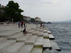 some people are sitting on concrete steps by the water