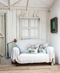 a white couch with two pillows on top of it in front of a wooden wall