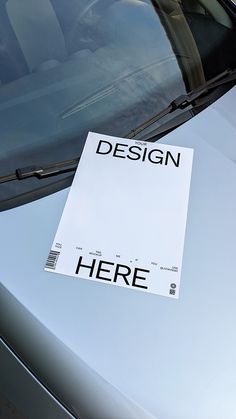 there is a sign on the windshield of a car that says, design here?