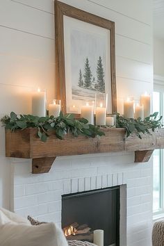 a mantle with candles and greenery on it in front of a fireplace mantel