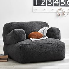 a gray chair with a football on it in front of a white wall and clock