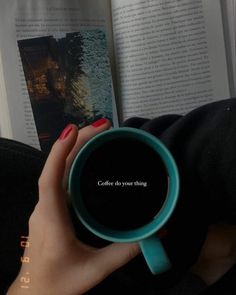 a woman holding a coffee cup in front of an open book