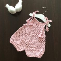 a crocheted baby romper and pacifier laying on a table next to it