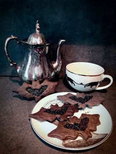 a plate with some cookies on it next to a tea pot