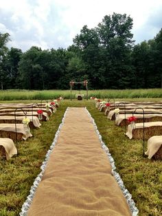 an outdoor ceremony setup with tables and chairs covered in burlocks, flowers and ribbons