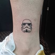 a star wars tattoo on the ankle with a storm trooper helmet and sunglasses drawn on it