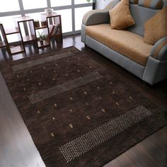 a living room area with a couch, chair and rug on the hardwood flooring