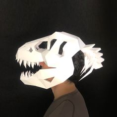 a person wearing a paper mask with a dinosaur's head on it, against a black background