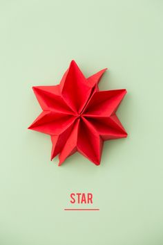 a red origami star on a green background with the word star below it