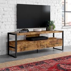 an entertainment center with a flat screen tv mounted to it's side, in front of a brick wall