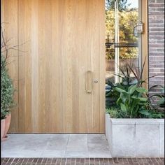 a wooden door is shown in front of a brick building with potted plants on the side