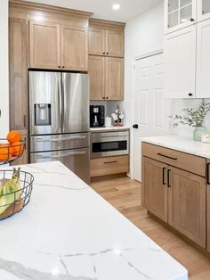 a modern kitchen with stainless steel appliances and wood cabinetry, along with white marble countertops