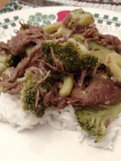 a white plate topped with meat and broccoli covered in sauce on top of rice