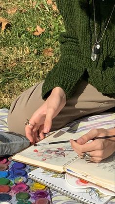 a woman is sitting on the ground with her hand on an open book and looking at it