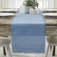 a blue table runner on top of a wooden table with white plates and silverware