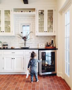 a small child is standing in front of an oven and looking at something on the counter