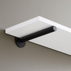 a black and white shelf mounted to the side of a wall with a light on it