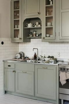 a kitchen filled with lots of gray cabinets and white tile backsplashes on the walls